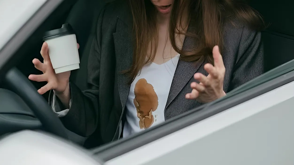 Femme avec une tache de café sur son t-shirt à l’intérieur de la voiture
