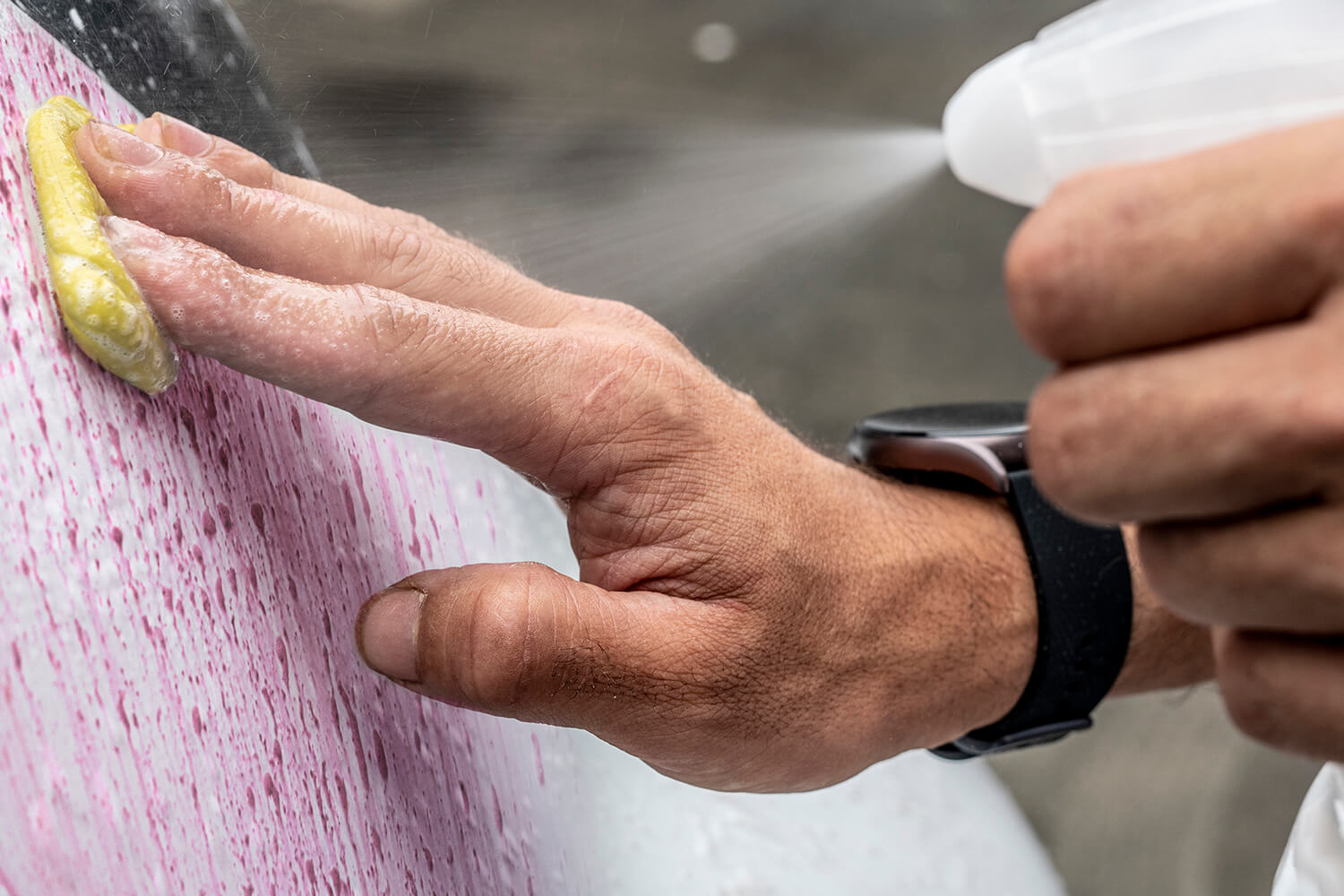 Main d’un homme frottant la carrosserie d’une voiture avec une claybar de couleur jaune