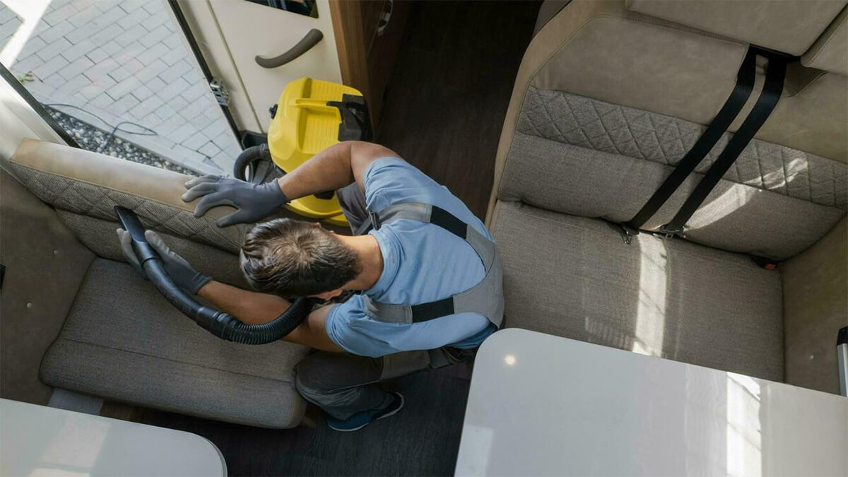 Homme aspirant la sellerie d’un siège de camping-car