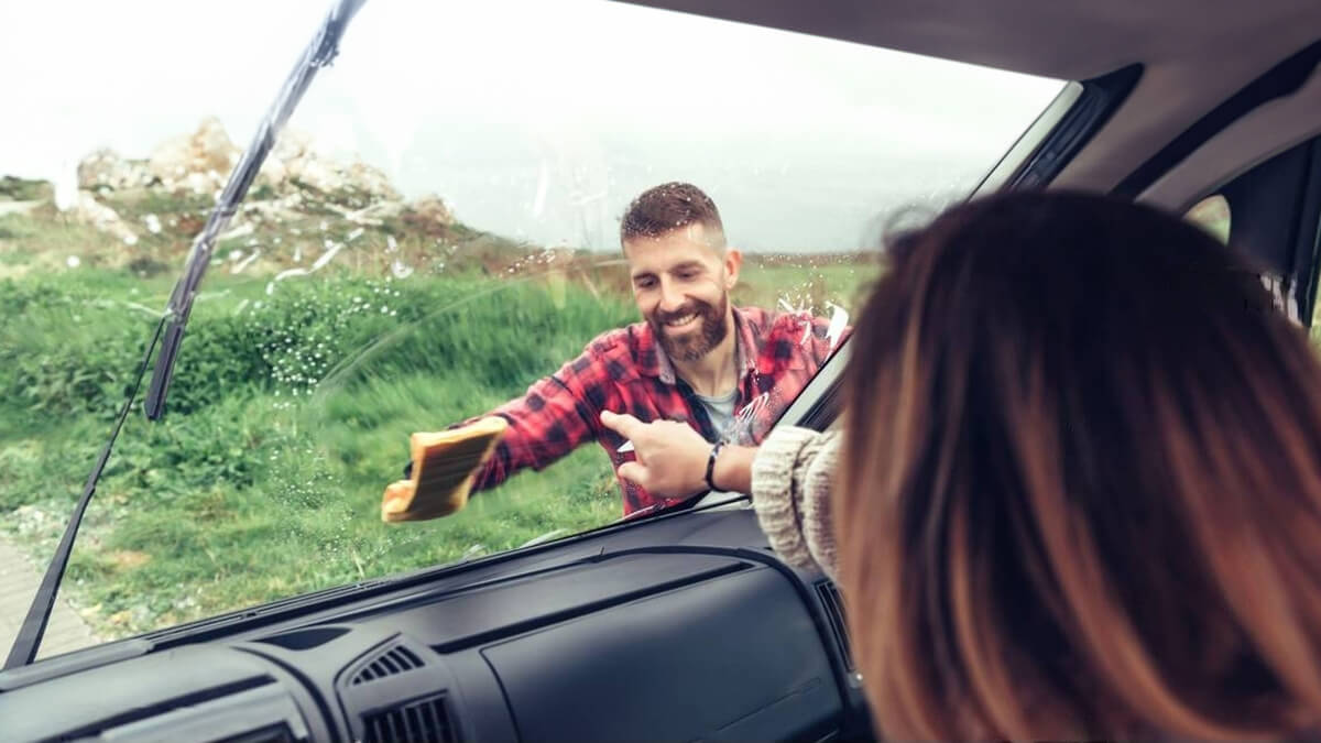Homme nettoyant le pare-brise d’un camping-car par l’extérieur