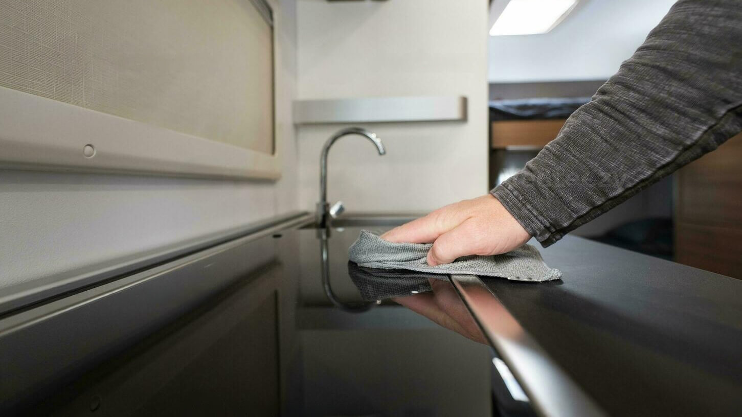 Personne nettoyant la cuisine d’un camping-car avec un chiffon en microfibre