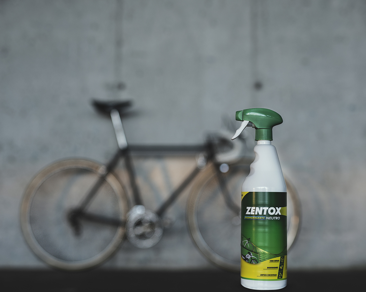 Bouteille de Zentox Dégraissant Neutre avec un vélo en arrière-plan appuyé contre un mur en béton gris
