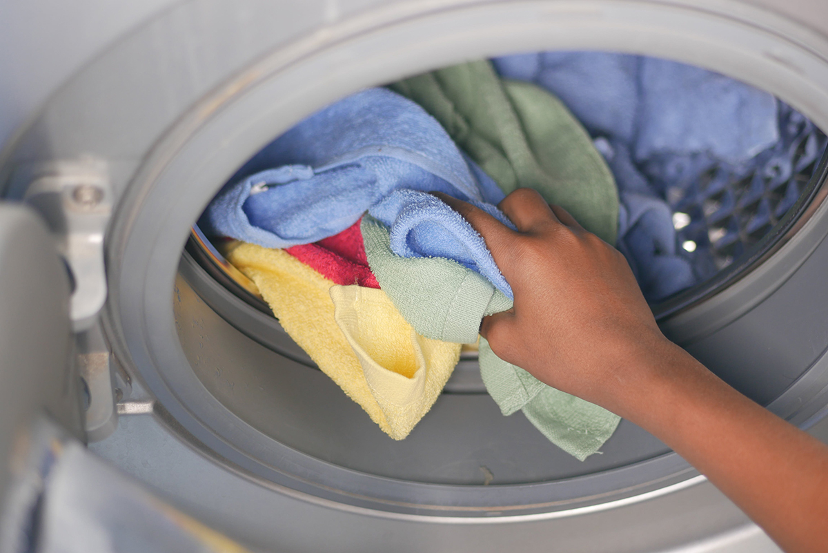Main plaçant des microfibres dans une machine à laver