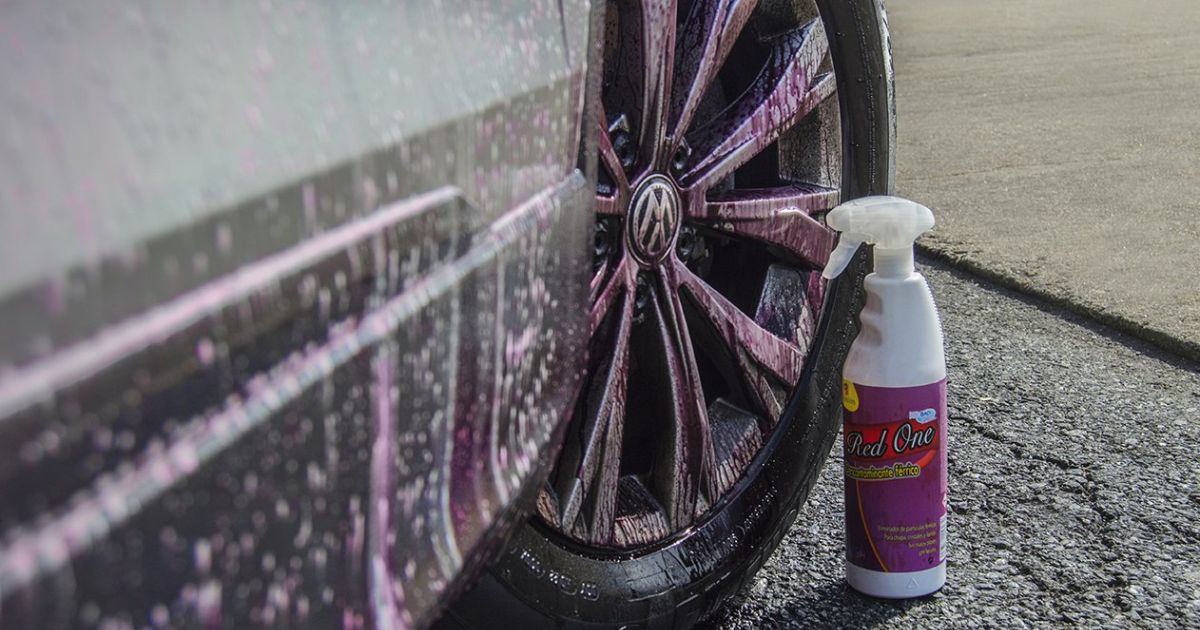 Une voiture dont les jantes sont en cours de nettoyage avec Red One Décontaminant Ferreux. Les jantes présentent des résidus d’un liquide violet qui s’écoule, indiquant que le produit agit pour éliminer la contamination ferreuse.