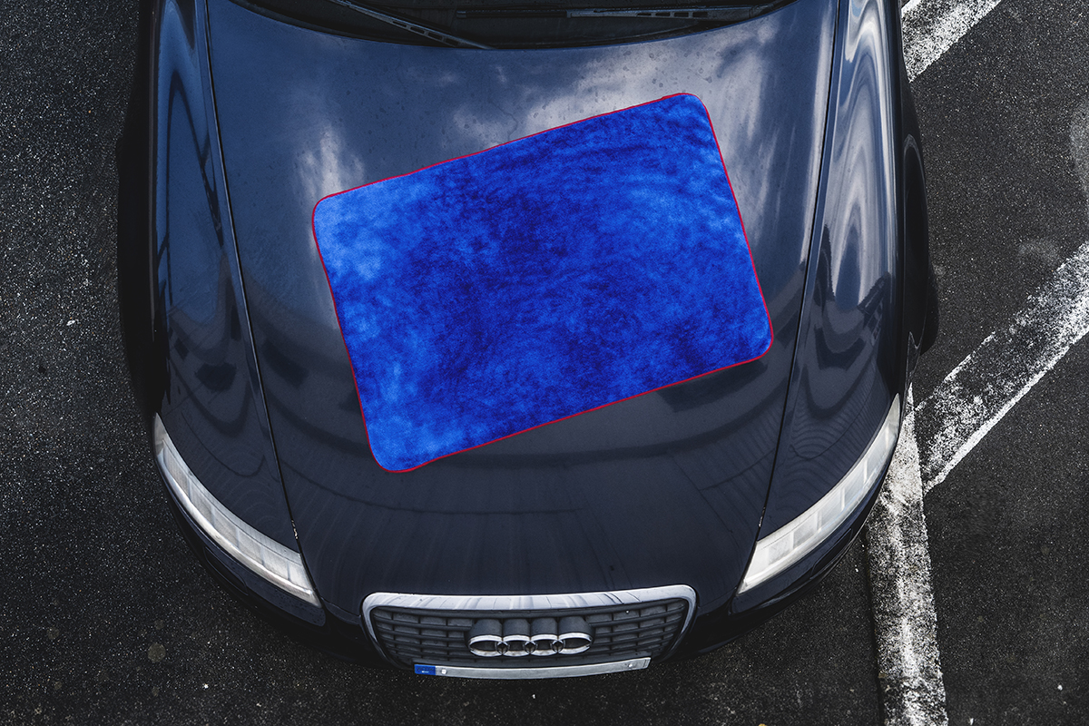 Serviette de séchage bleue sur le capot d’une voiture sombre